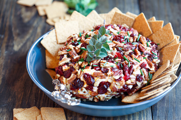 A colorful cheese ball surrounded by crackers on a wooden table.
