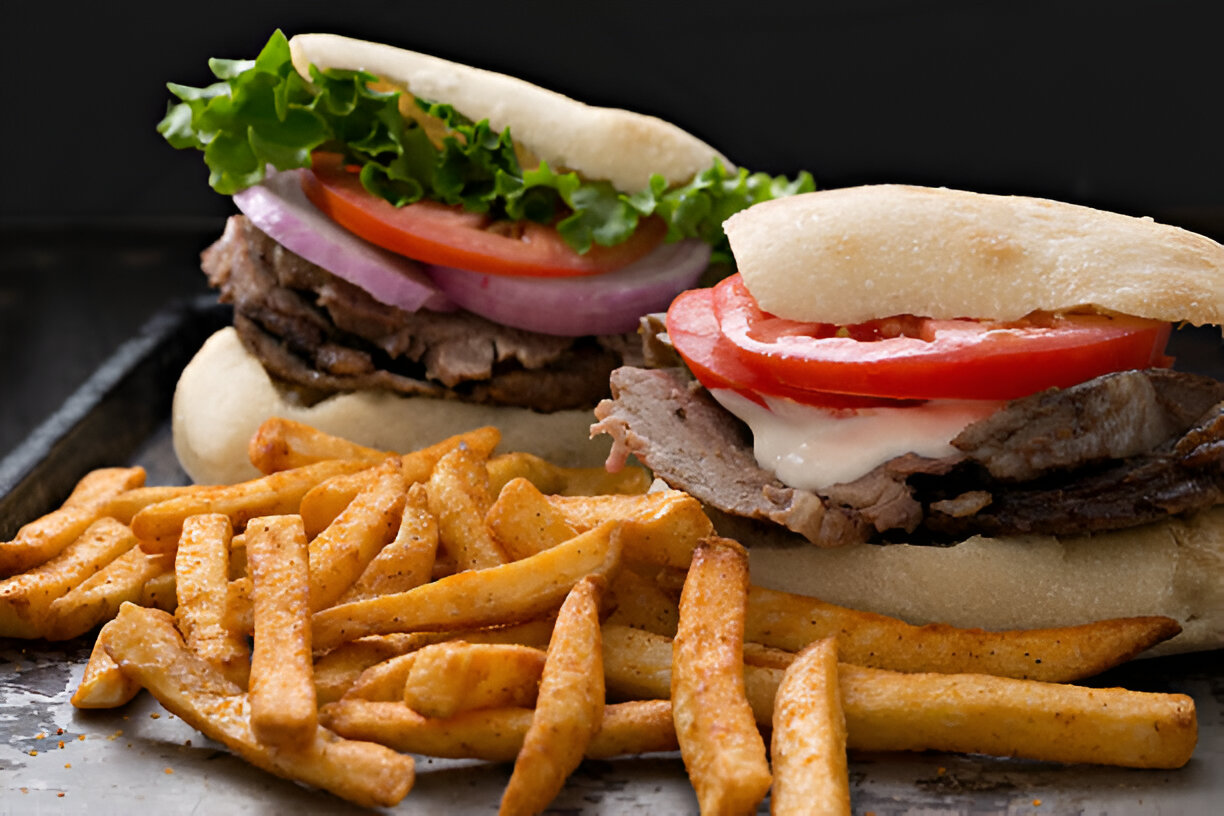 Two delicious sandwiches with beef, lettuce, tomatoes, onions, and sauce, served with crispy fries.