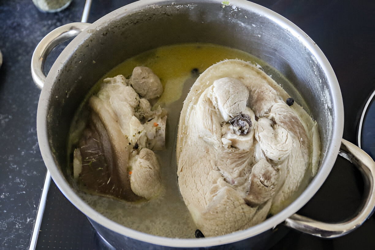 A pot containing two large pieces of meat simmering in broth.