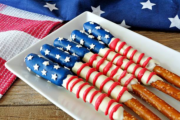 Chocolate-covered pretzel sticks decorated in red, white, and blue, resembling the American flag, arranged on a plate.