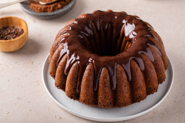 A chocolate bundt cake with a glossy chocolate glaze on a white plate.
