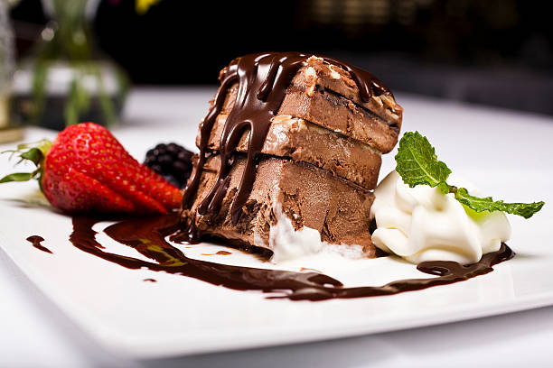 A delicious chocolate dessert with layers, topped with chocolate sauce, served with fresh strawberries and whipped cream.