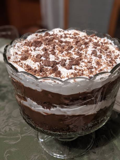 A glass bowl filled with layered chocolate dessert topped with whipped cream and chocolate shavings.