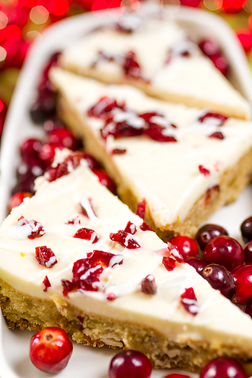 Three slices of cranberry cheesecake on a white dish surrounded by fresh cranberries.