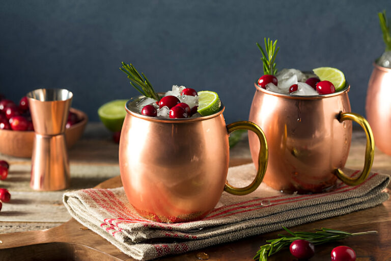Copper mugs filled with cranberry cocktails, garnished with lime and rosemary.
