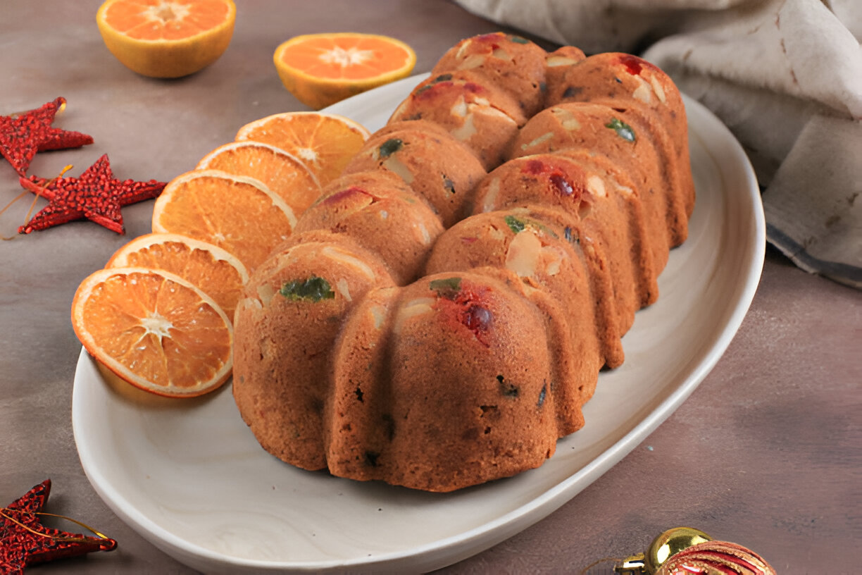 A beautifully arranged bundt cake on a platter with fresh orange slices.