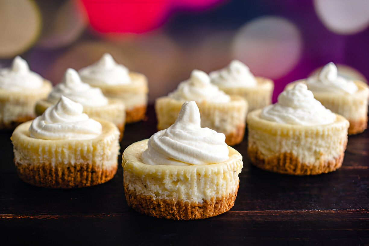 Mini cheesecakes topped with whipped cream on a wooden surface