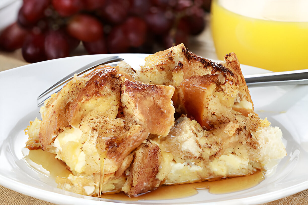 A close-up of a delicious bread pudding slice drizzled with syrup, served on a white plate.