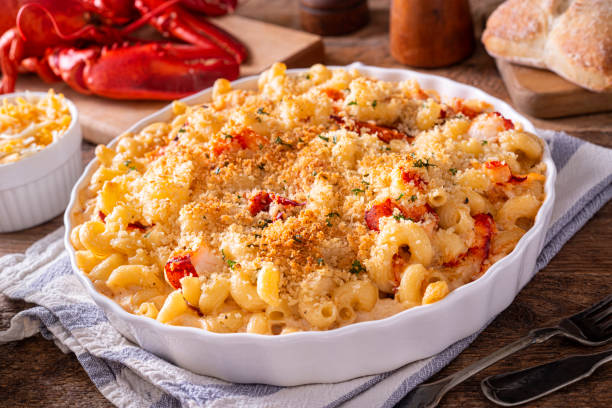 A delicious dish of lobster mac and cheese topped with breadcrumbs, served in a white dish with a cozy wooden background.