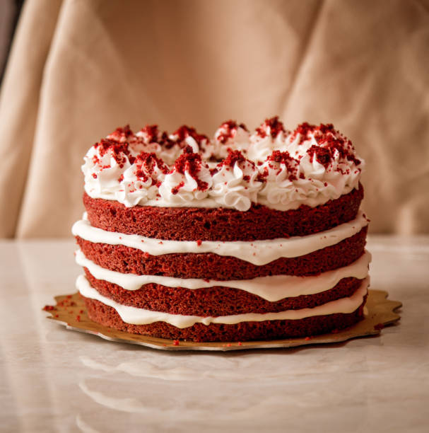 A delicious red velvet cake with three layers and cream cheese frosting, topped with red velvet crumbs.