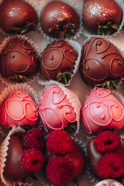 Assorted chocolate-covered strawberries in pink and brown, arranged with raspberries.