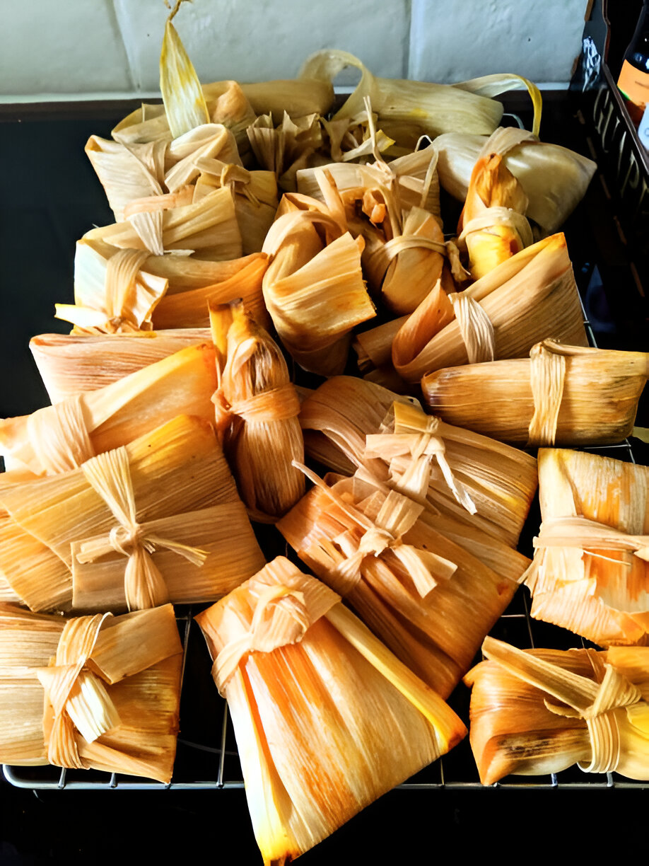A collection of wrapped tamales tied with strings, resting on a wire rack.