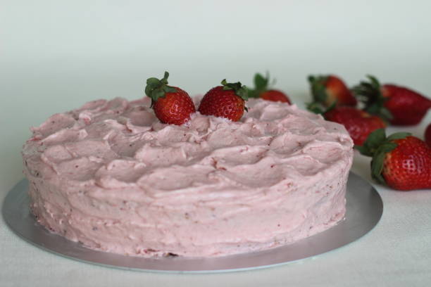 A beautifully decorated pink strawberry cake topped with fresh strawberries.