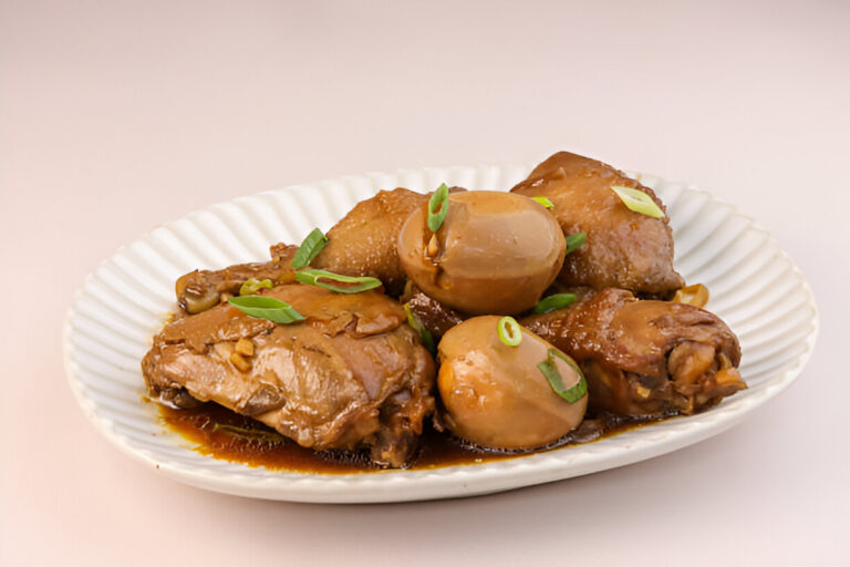 A plate of braised chicken pieces with eggs, garnished with green onions.
