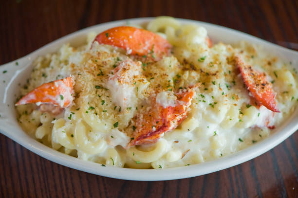 A creamy lobster pasta dish served in a white oval dish, garnished with breadcrumbs and herbs.