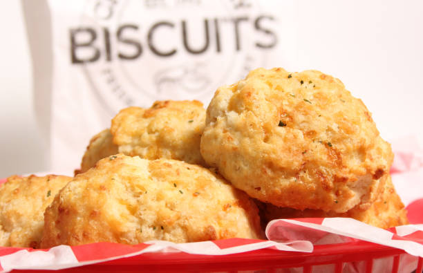 A basket of freshly baked biscuits with a paper bag in the background labeled 'BISCUITS'.