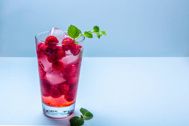 A refreshing glass of raspberry beverage with ice and mint leaves