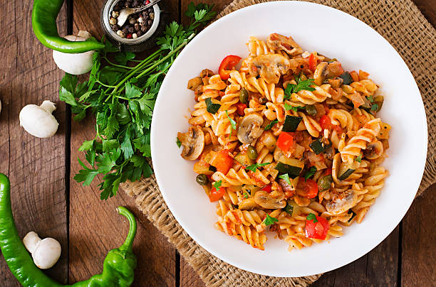 A plate of colorful fusilli pasta with vegetables, served on a wooden table