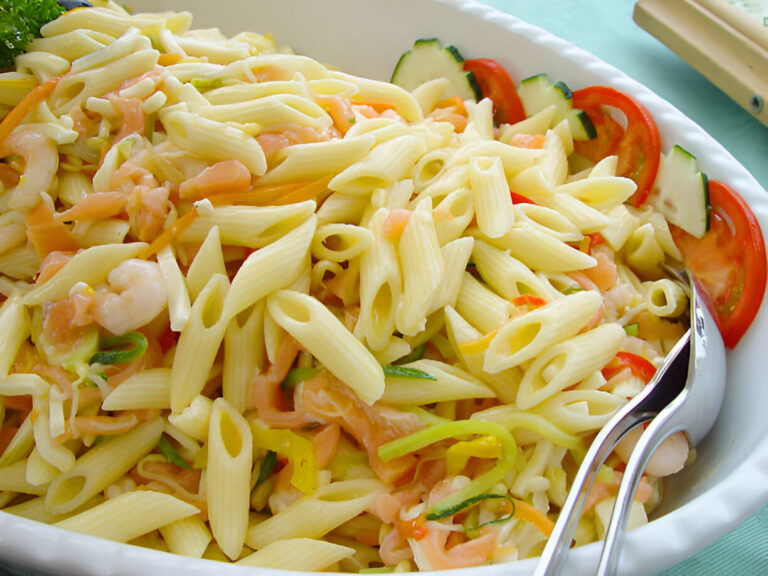 A close-up of a bowl of pasta salad with shrimp, vegetables, and penne pasta.
