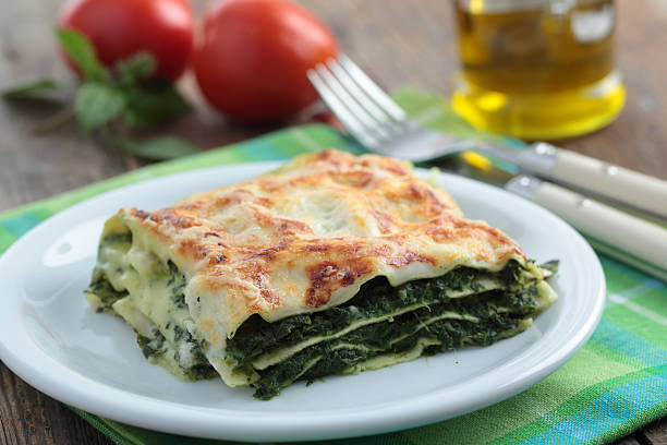 A serving of baked vegetable lasagna on a decorative white plate, garnished with fresh herbs.