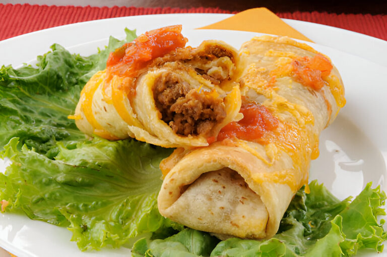 Two enchiladas on a bed of lettuce topped with cheese and salsa