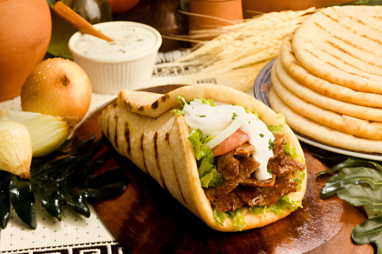 A delicious flatbread wrap filled with grilled meat, lettuce, tomato, and a creamy sauce, served with fresh vegetables and tortillas in the background.