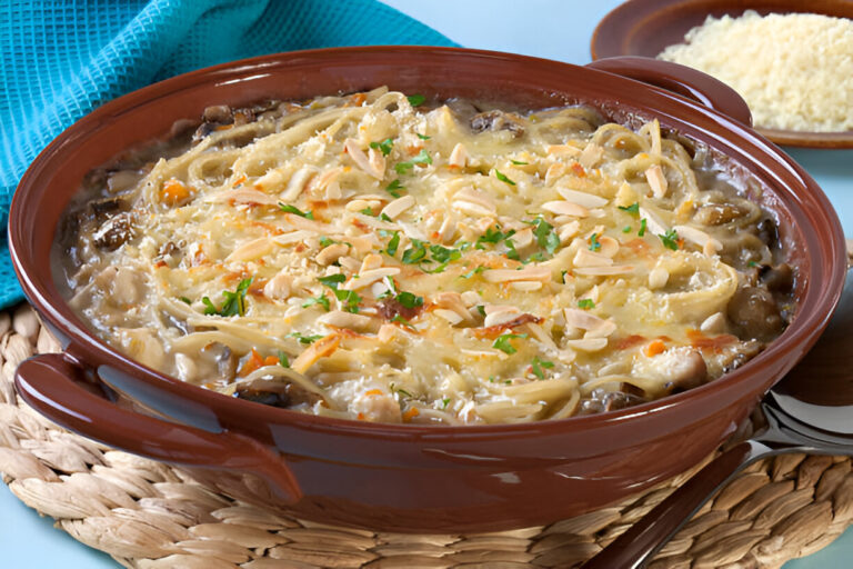 A baked pasta dish topped with cheese and sliced almonds, served in a brown ceramic dish.