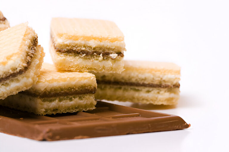 Layers of wafer cookies with a chocolate bar in the foreground