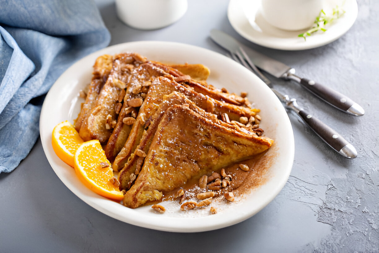 Deliciously plated French toast topped with nuts and served with orange slices