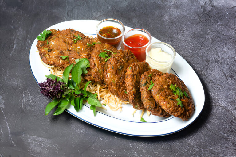 A plate of savory patties served with dipping sauces and garnished with greens.