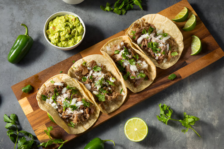 Delicious tacos filled with meat, topped with onions and cilantro, served with guacamole and lime