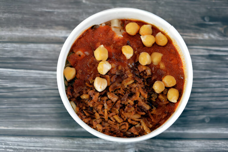 A bowl of spicy chickpea dish topped with crispy fried onions and boiled chickpeas.