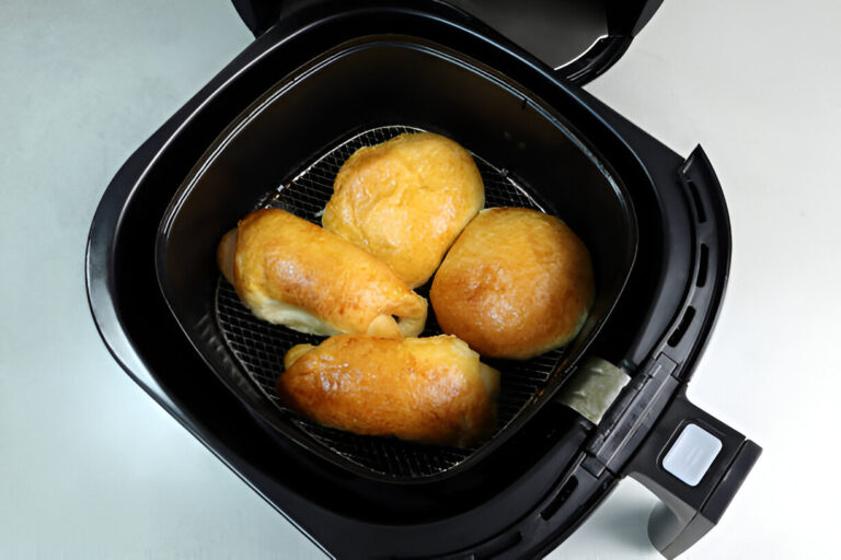 Four golden-brown rolls in an air fryer basket