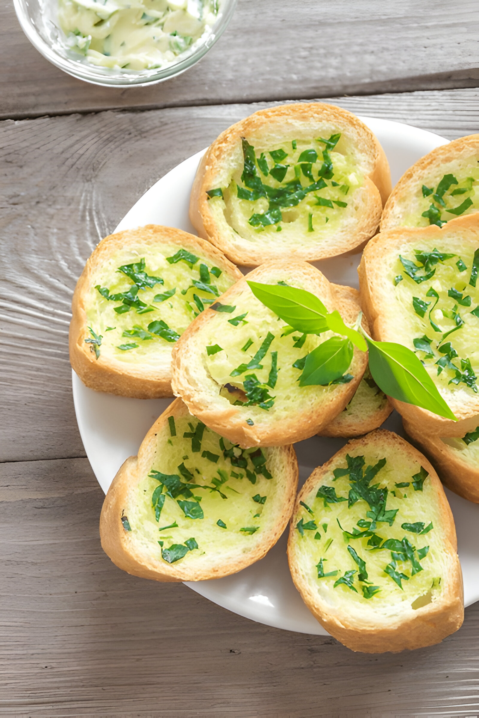 A plate of bread slices topped with chopped herbs, placed on a wooden surface.