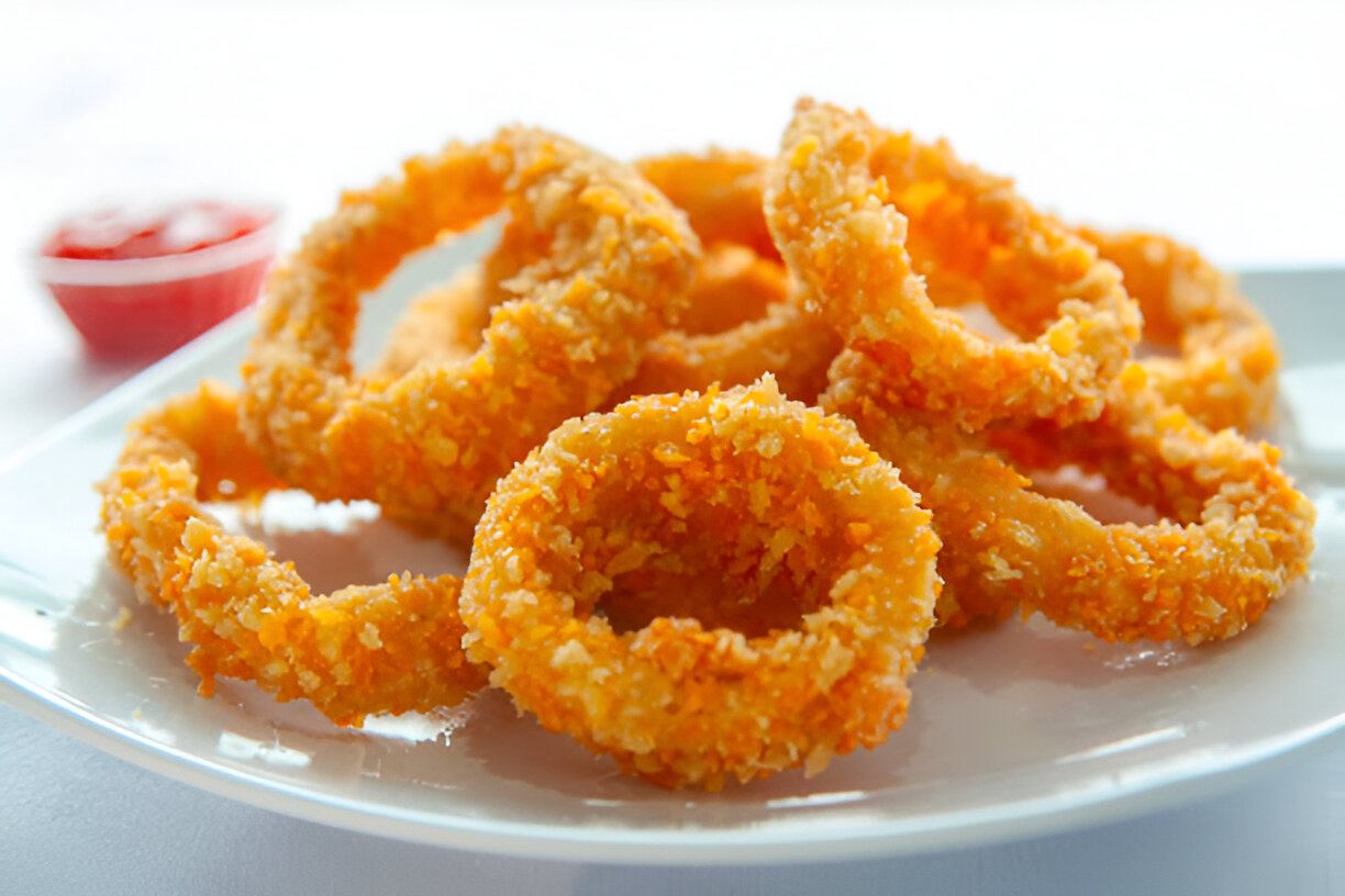 Plate of crispy fried onion rings served with a side of ketchup.