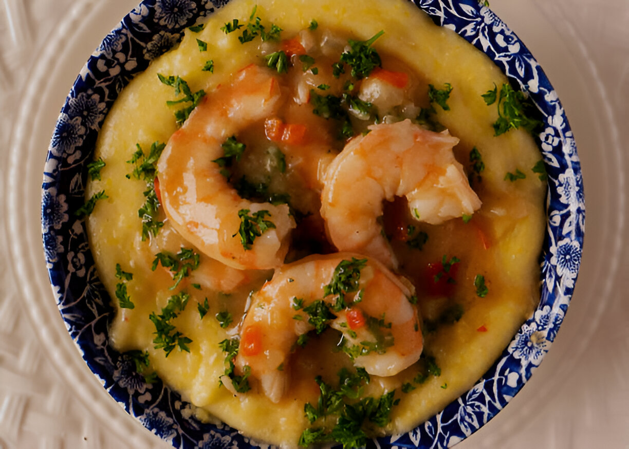 A bowl of shrimp and grits garnished with parsley, placed on a decorative plate.