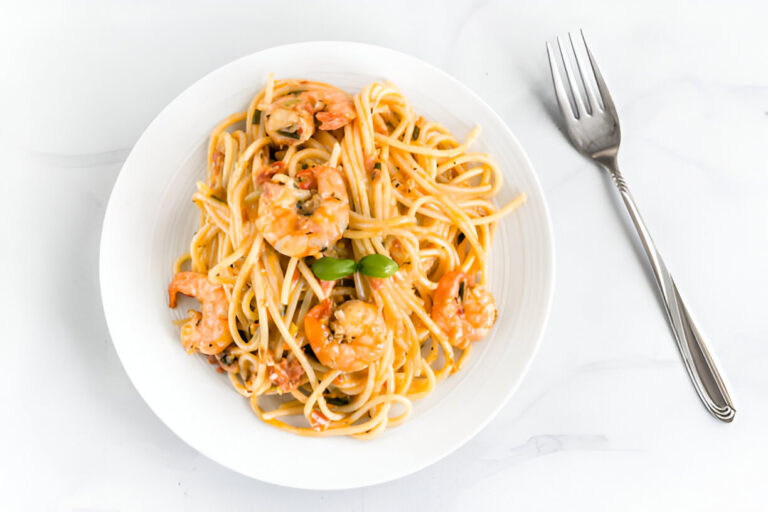A delicious plate of shrimp pasta with a light sauce, garnished with fresh basil.