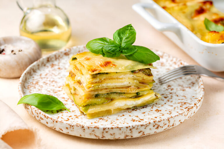 A beautifully arranged plate of lasagna with fresh basil on top, set against a soft background.