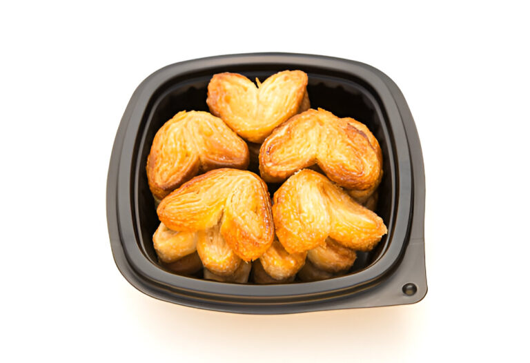 A close-up of heart-shaped puff pastries in a black container.