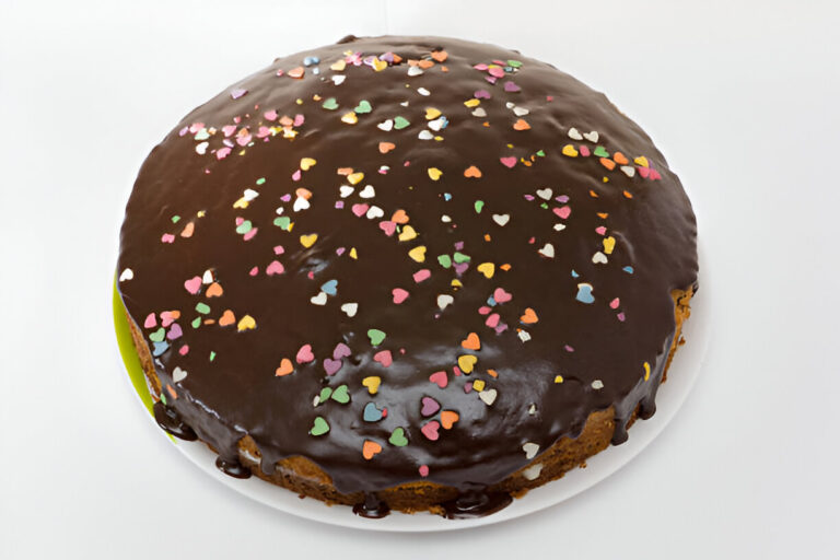 A round chocolate cake with colorful heart-shaped sprinkles on top.