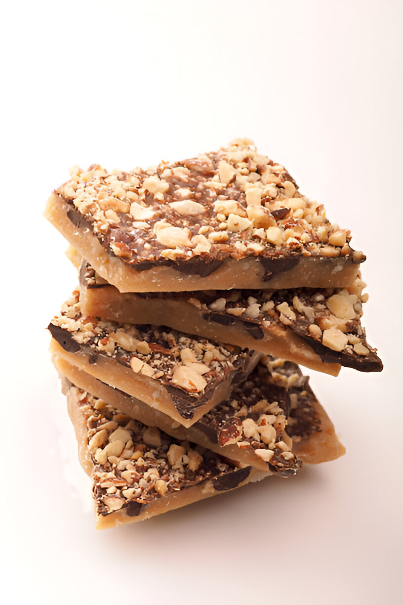 Stack of chocolate toffee bars topped with crushed nuts.
