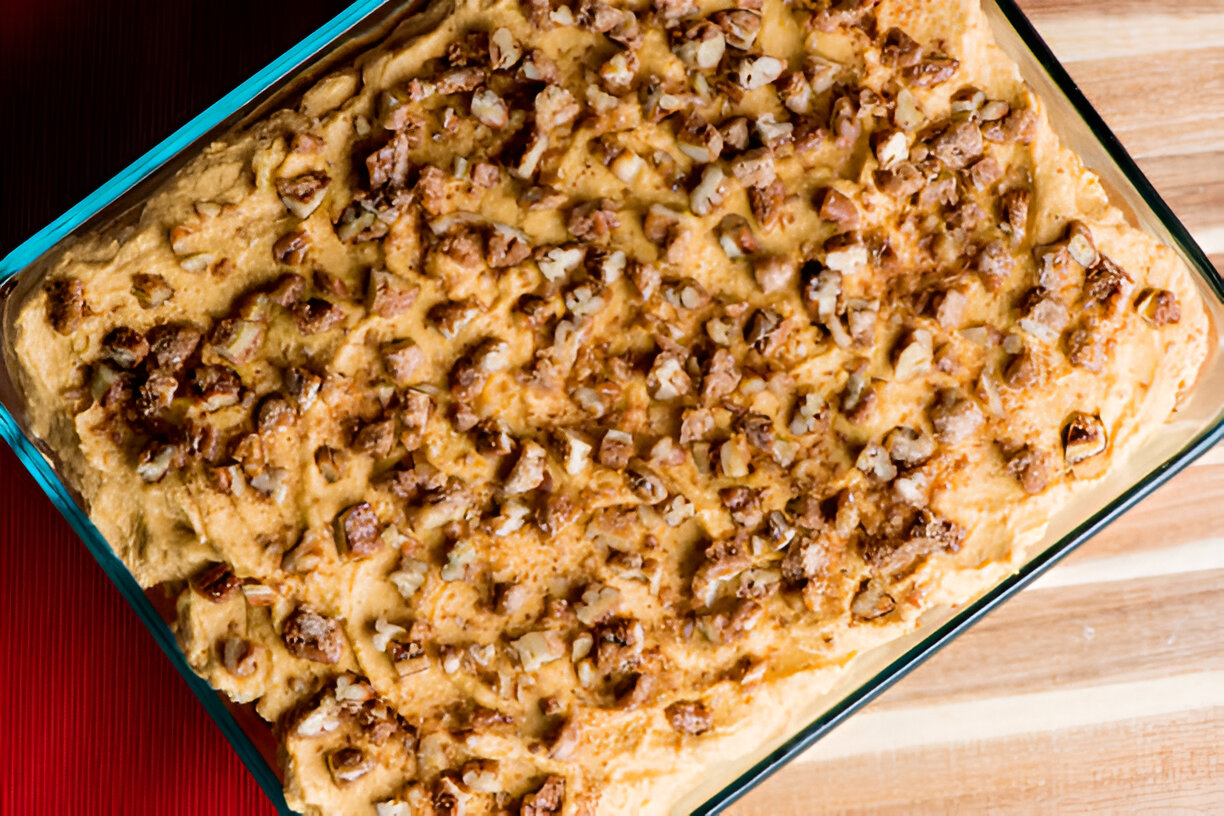 Baked dish topped with chopped nuts in a glass baking dish on a wooden surface.