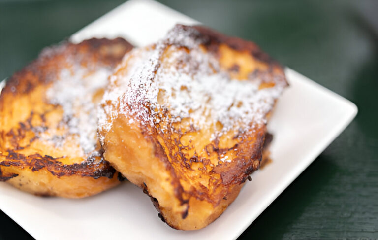 Plate of golden-brown French toast dusted with powdered sugar