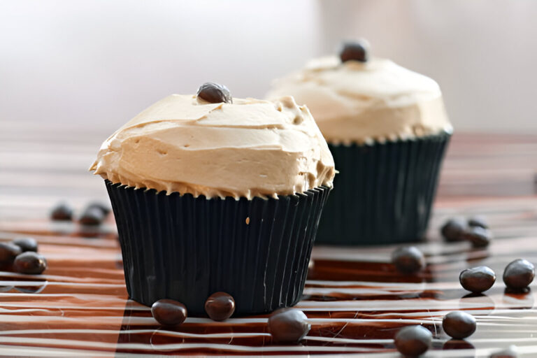 Two beautifully frosted cupcakes with a coffee buttercream topping and chocolate accents.