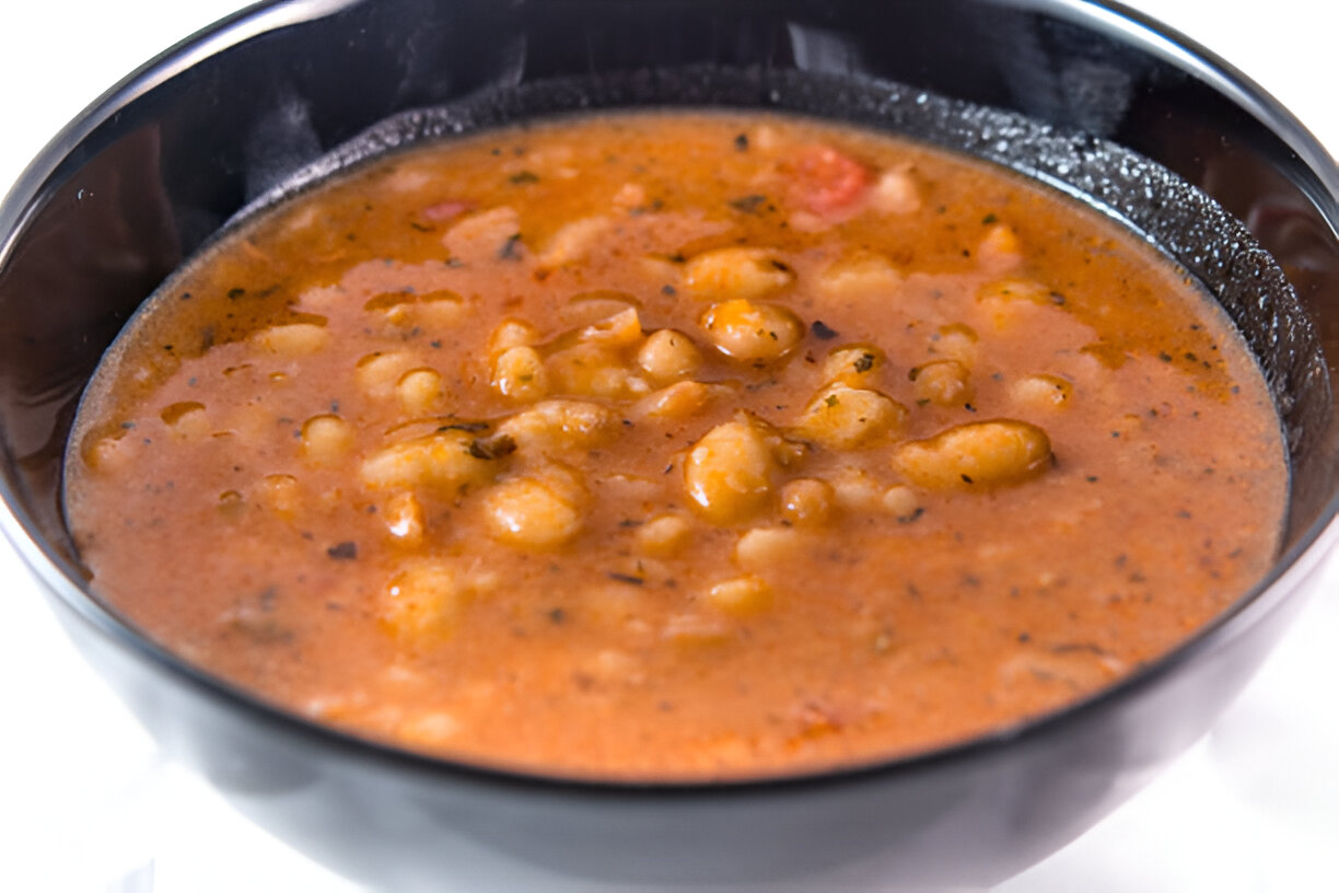 A close-up view of a steaming bowl of hearty bean soup.