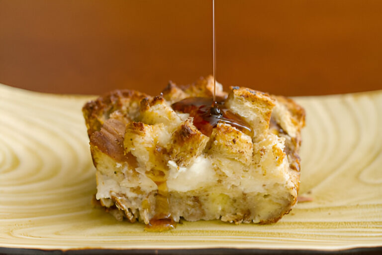 A slice of bread pudding drizzled with syrup on a decorative plate.