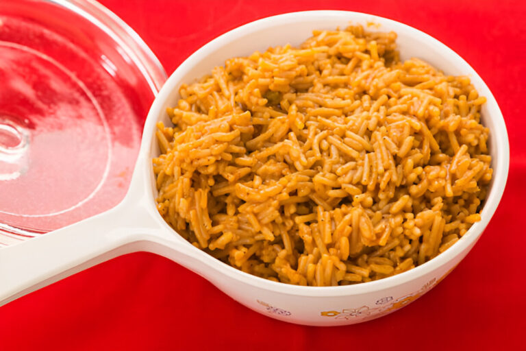 A bowl of rice served on a bright red table.