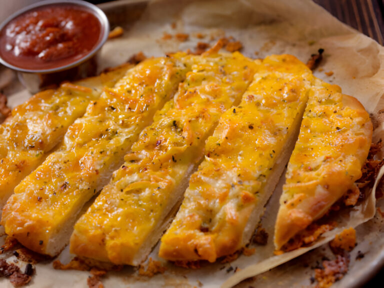 A platter of cheesy breadsticks with marinara sauce on the side.