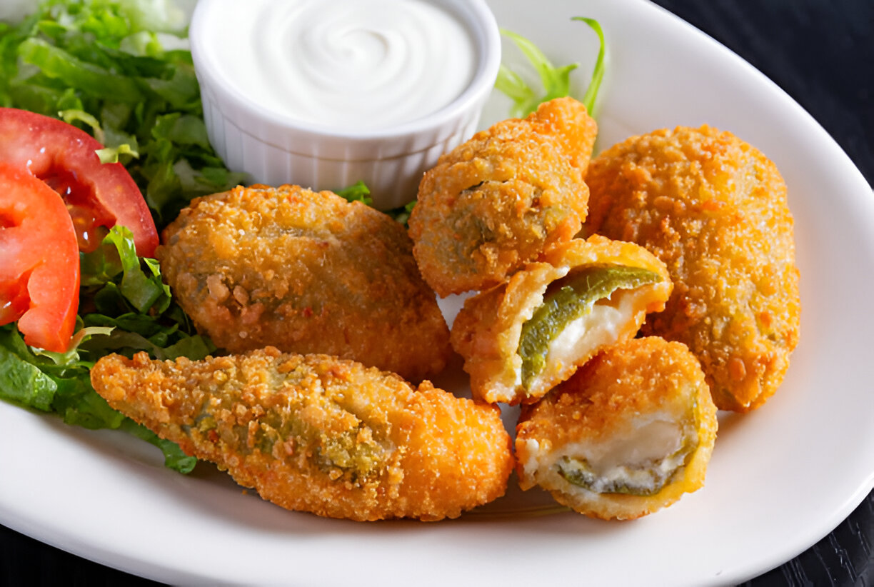 A plate of crispy jalapeño poppers served with sour cream and fresh salad.