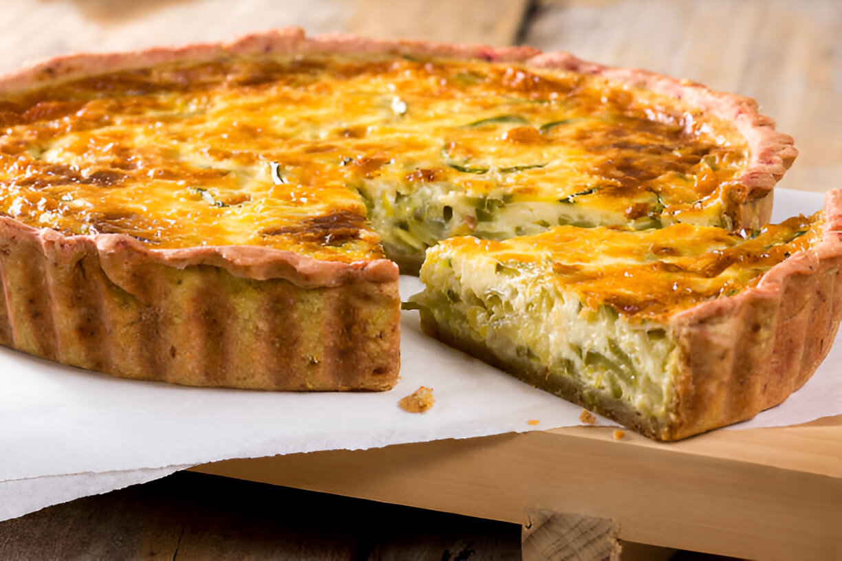A delicious vegetable quiche on a wooden serving board, with a slice cut out revealing the filling.